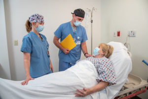 Two nurses talking with patient after surgery
