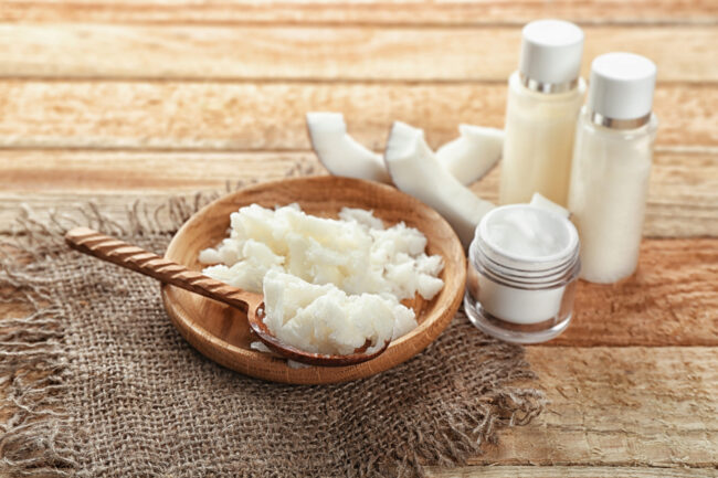 Plate with fresh coconut oil and bottles on wooden table