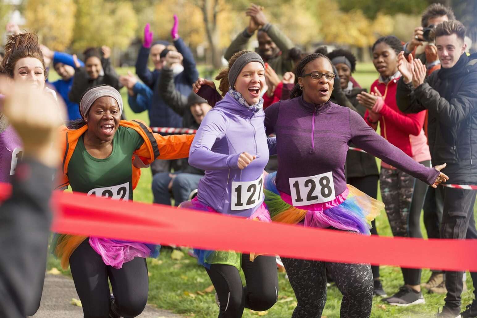 Enthusiastic female runners in tutus nearing finish line at charity run