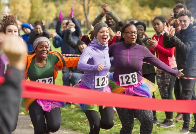 Enthusiastic female runners in tutus nearing finish line at charity run