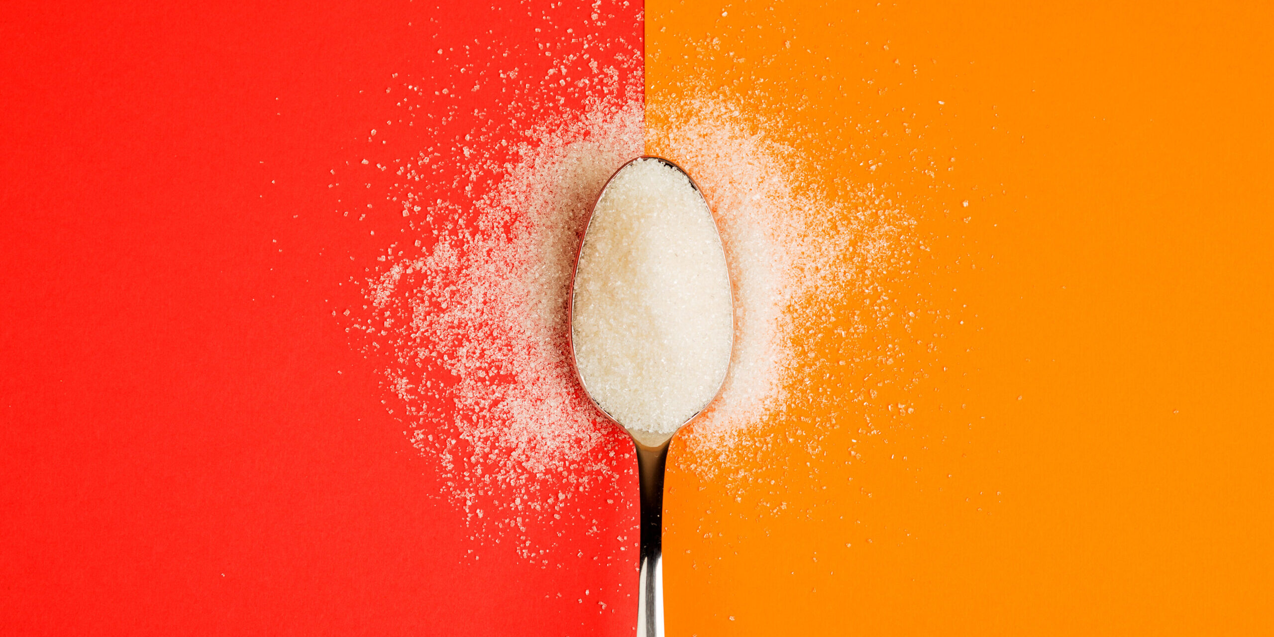 sugar with spoon on red and yellow background