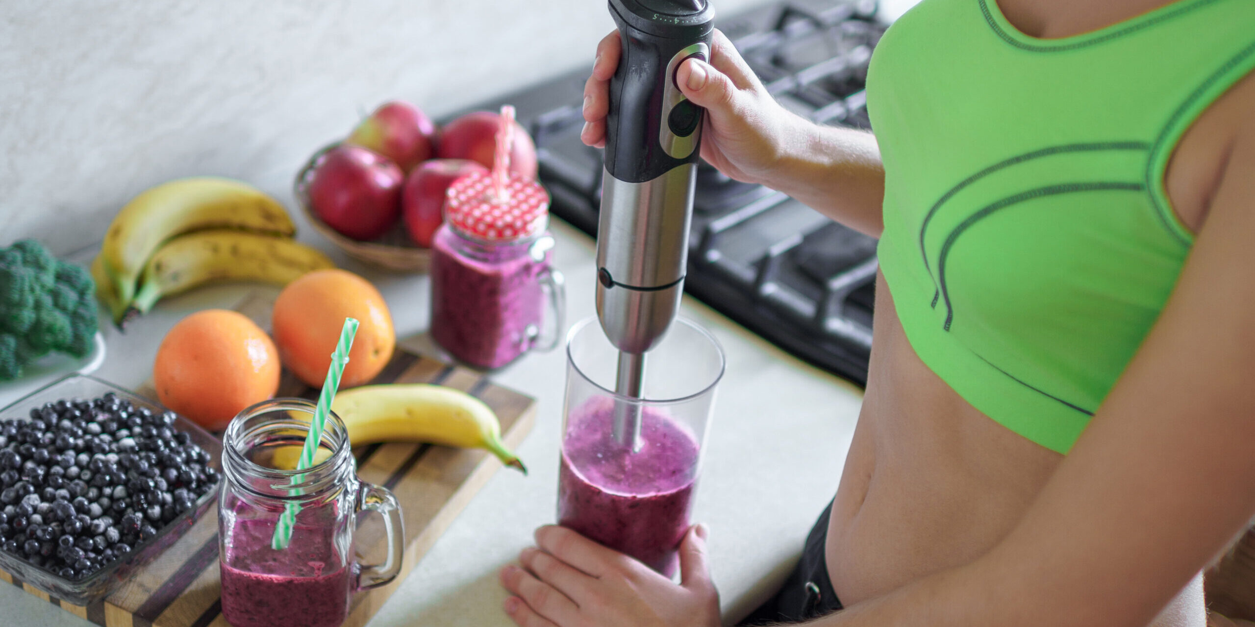 Sports healthy woman cooking fresh blueberry smoothie using hand