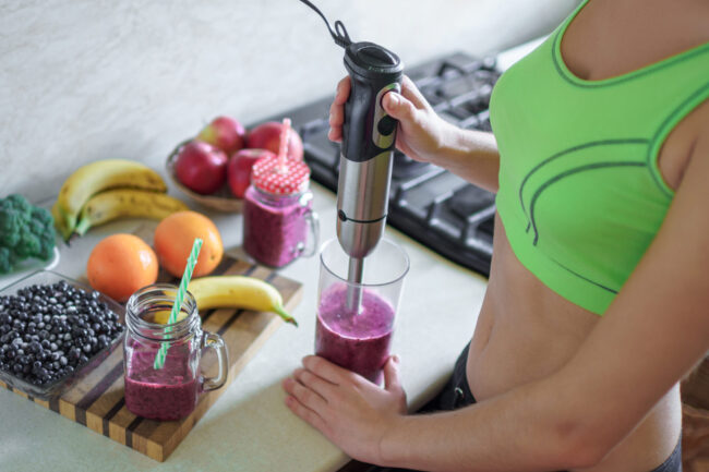 Sports healthy woman cooking fresh blueberry smoothie using hand
