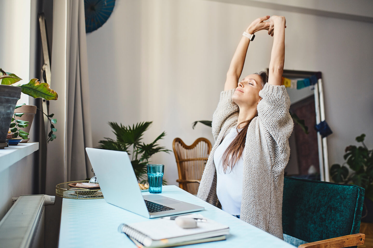 Freelancer with eyes closed stretching arms sitting at desk