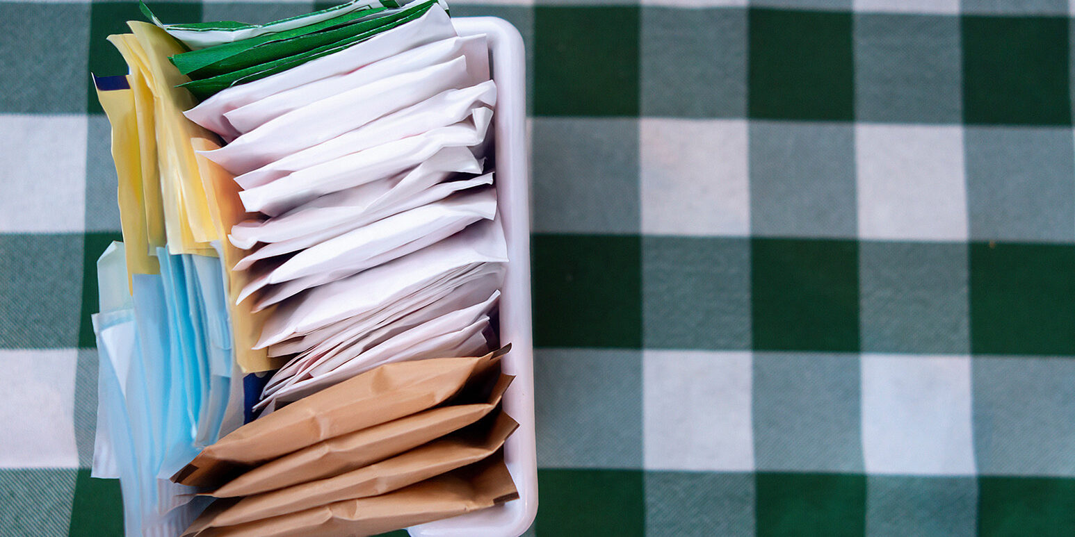 sugar packets on a Checkered white and green table cloth
