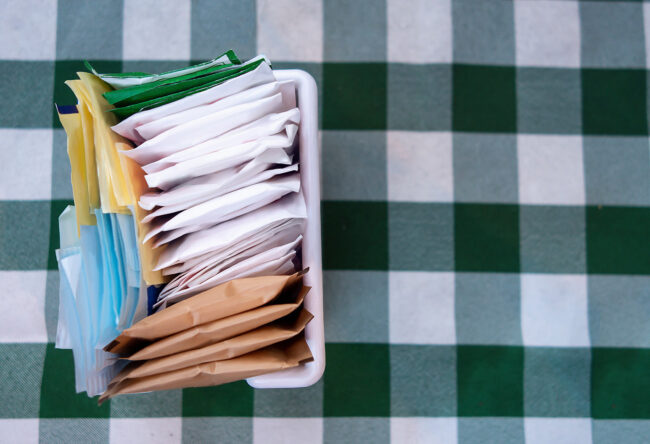 sugar packets on a Checkered white and green table cloth