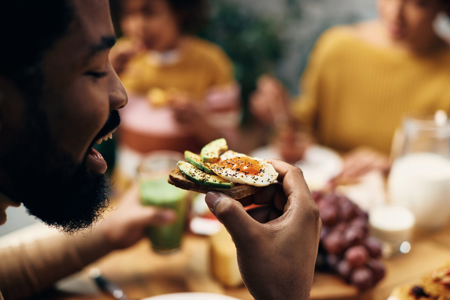 Close-up of black man eating healthy sandwich at home.