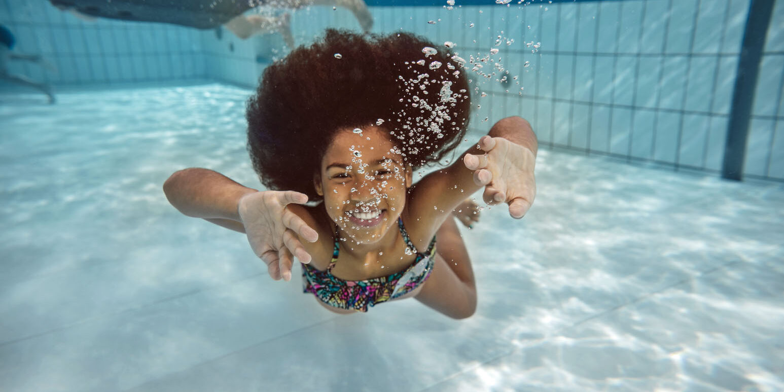 Girl swimming under water in swimming pool