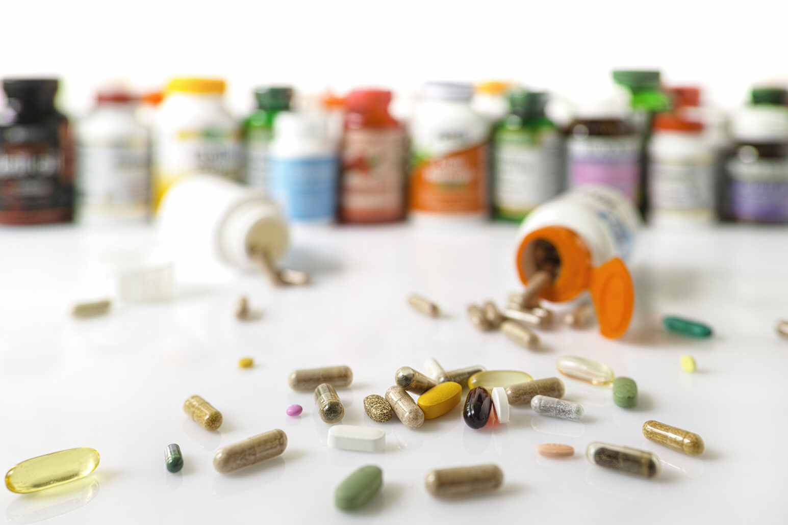 Many nutritional health supplements and vitamins in capsules, tablets and in bottles on a white background, shallow depth of focus.