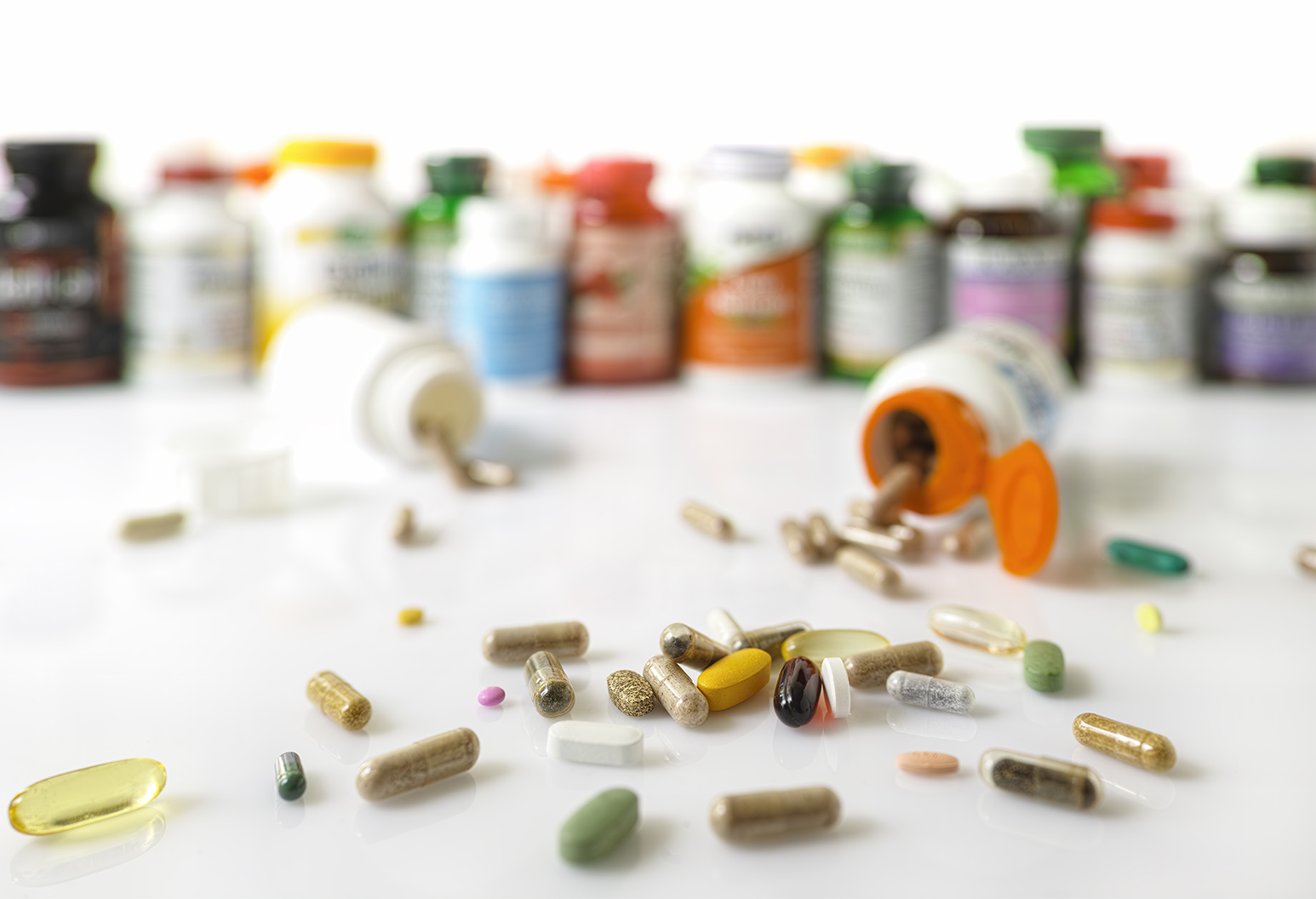 Many nutritional health supplements and vitamins in capsules, tablets and in bottles on a white background, shallow depth of focus.