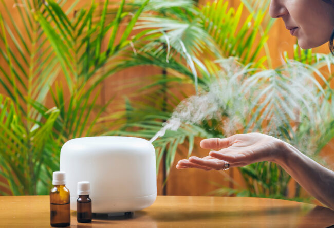 Woman Enjoying Aroma Therapy Steam Scent from Home Essential Oil Diffuser or Air Humidifier