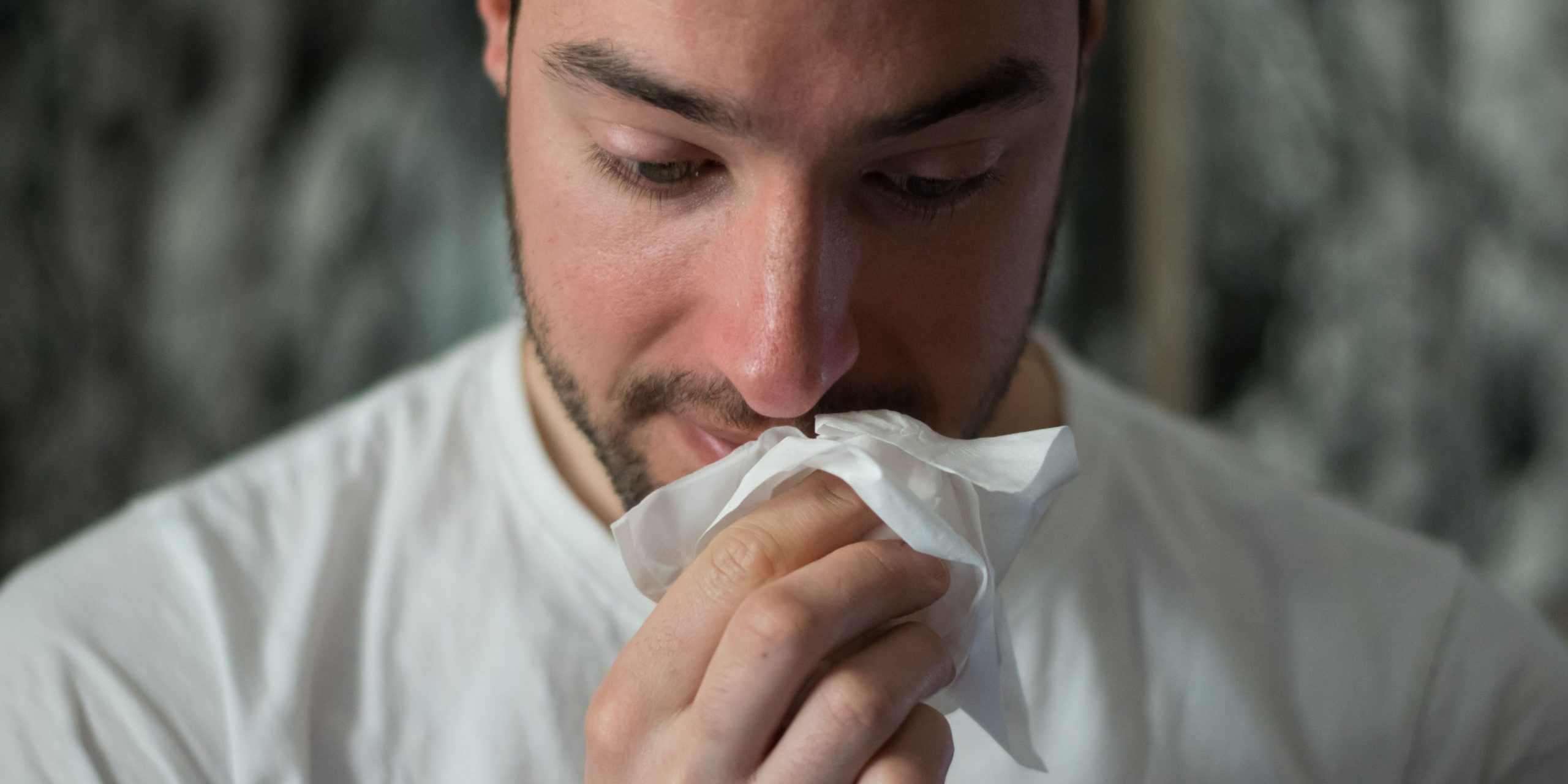 Man wiping nose with tissue