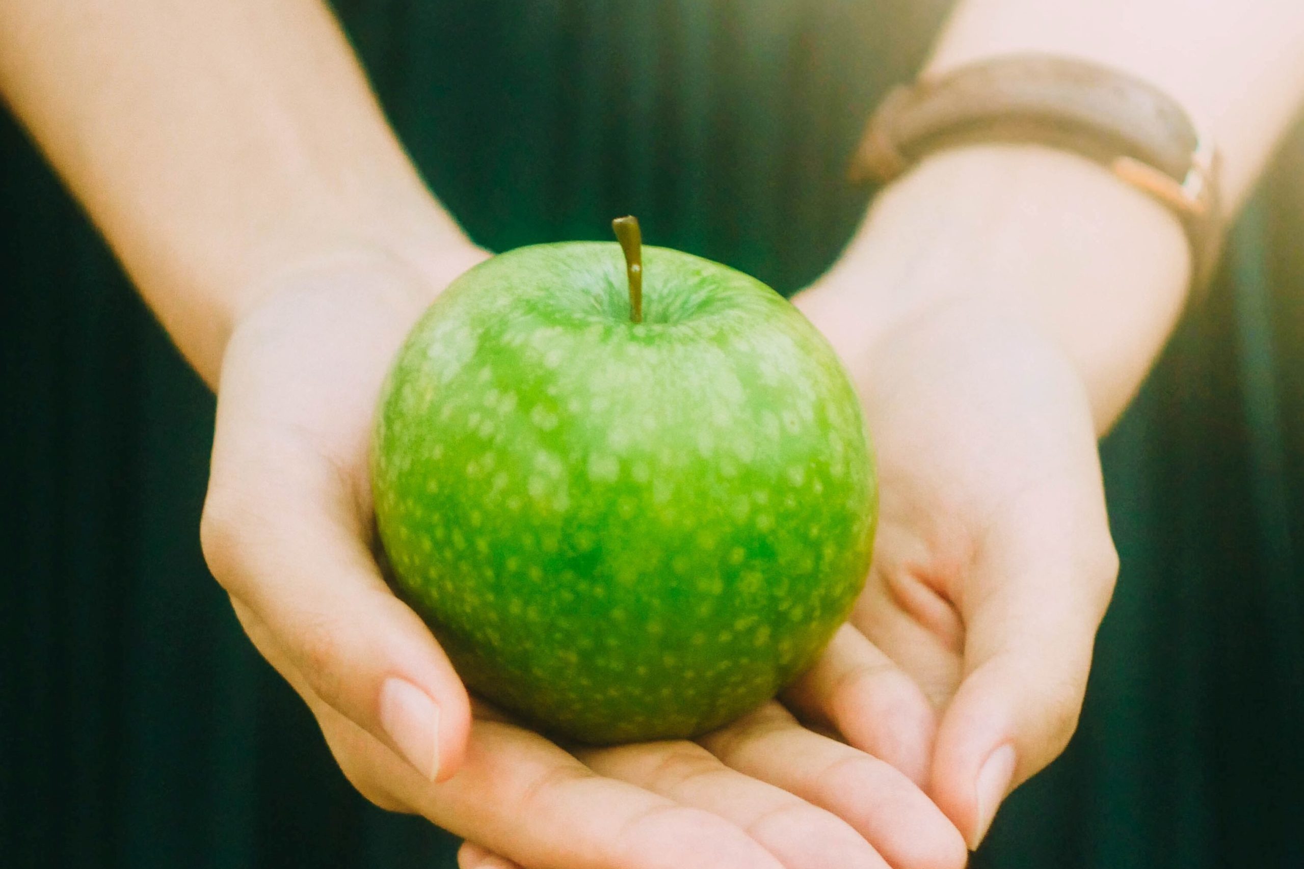 Hands holding apple Woman holding a green apple in her hands