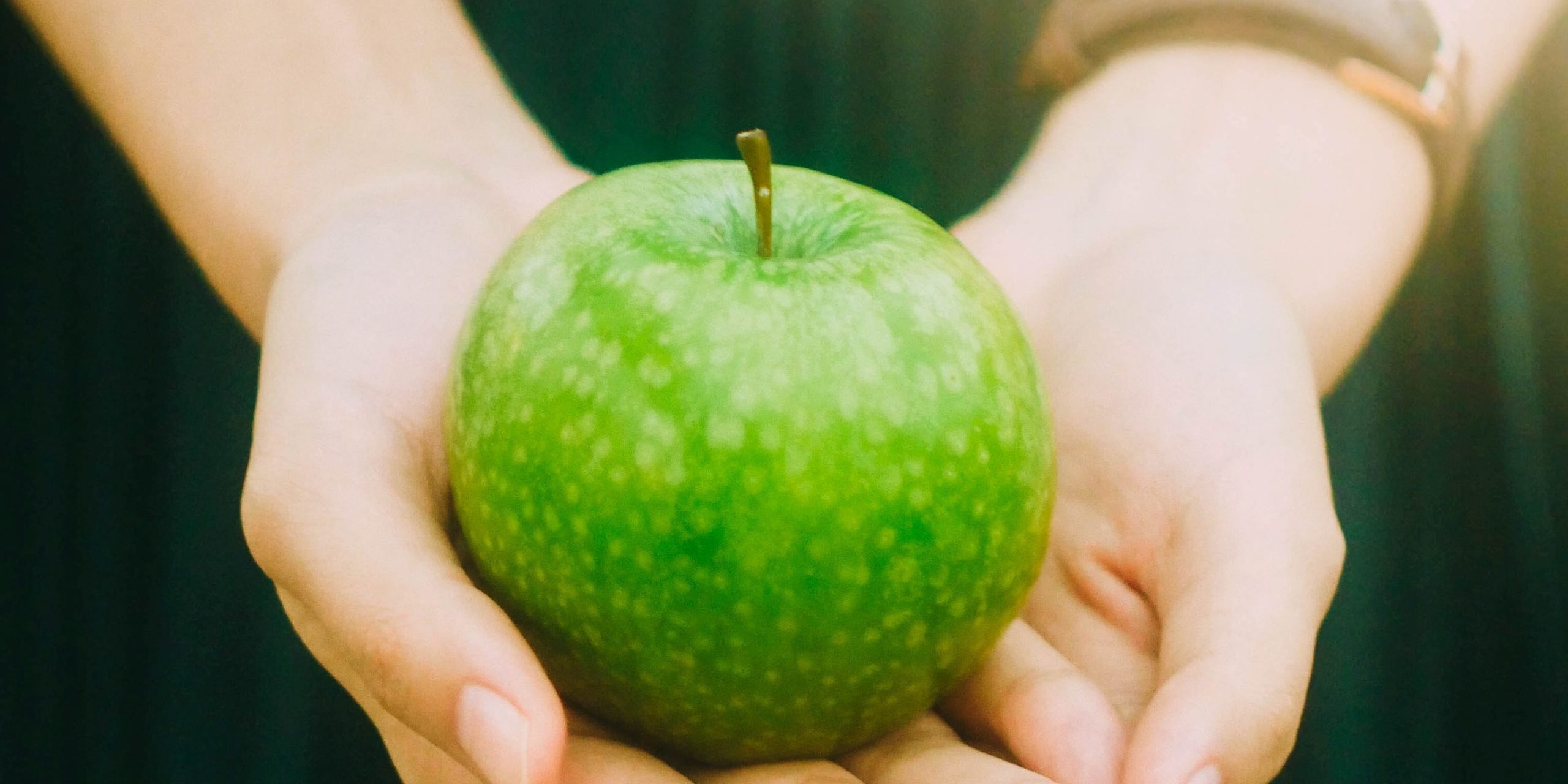 Hands holding apple Woman holding a green apple in her hands