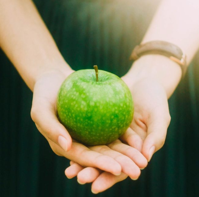 Hands holding apple Woman holding a green apple in her hands