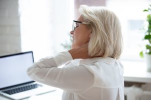 Woman sitting in front of computer with neck pain