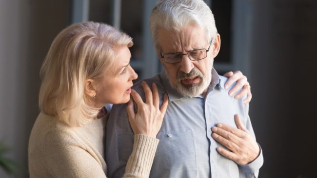 Man grabbing his chest and woman comforting him