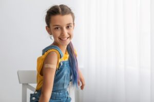 Young girl showing band aid on her arm where she had a vaccination