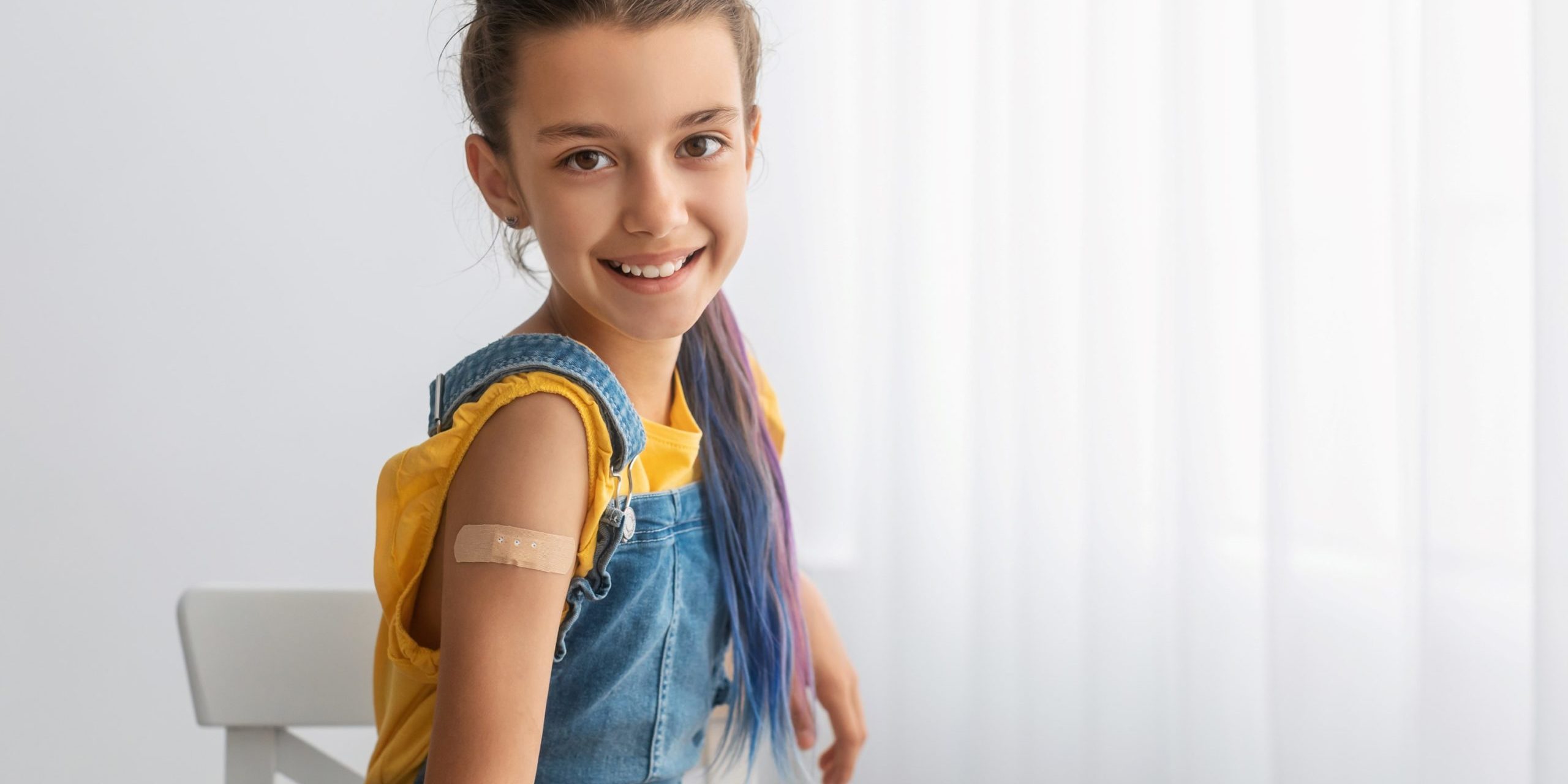 Young girl showing band aid on her arm where she had a vaccination