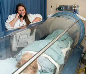 Nurse talking to a woman laying in a hyperbaric oxygen therapy chamber