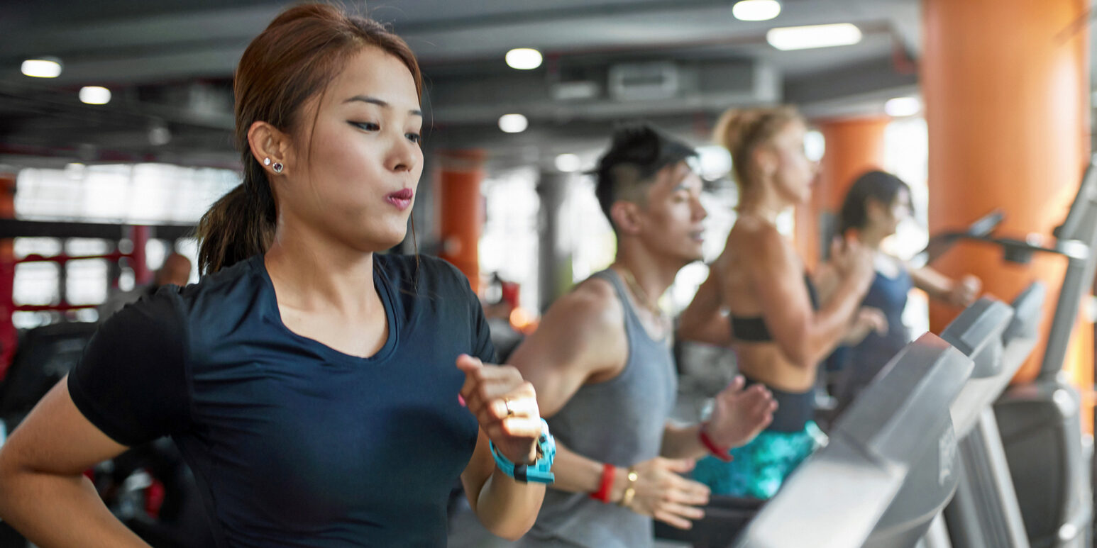 Determined woman running on treadmill in gym