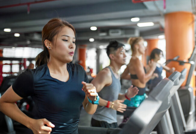 Determined woman running on treadmill in gym