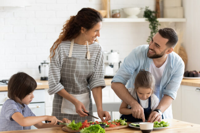 Full family with kids chatting and preparing healthy vegetarian salad