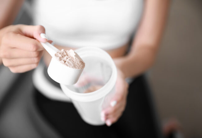 Sporty young woman with protein at home, closeup